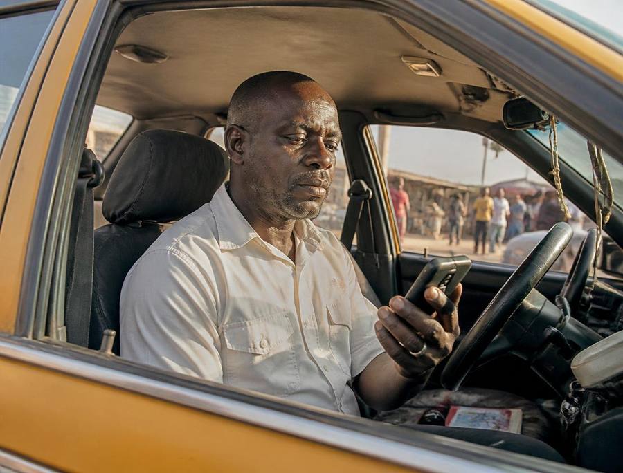 Male driver checking his phone between trips on a busy African city street